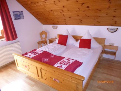 a bedroom with a wooden bed with red pillows at Landgasthaus Gemsennest in Feldberg