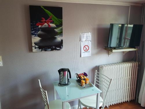 mesa y sillas con mesa azul y TV en Hotel des Voyageurs, en Mayenne