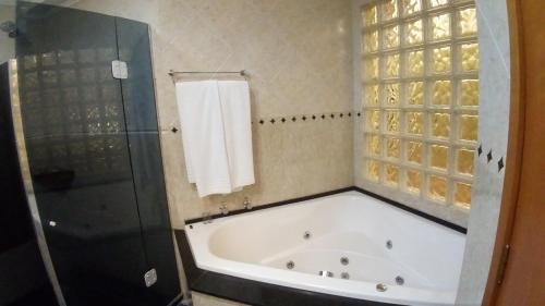 y baño con bañera, ducha y toalla. en Hotel Presidente, en Uruguaiana