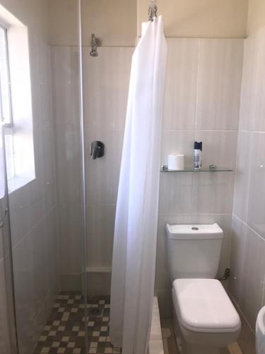 a bathroom with a toilet and a shower with a shower curtain at Concord Christian Guesthouse in Durban