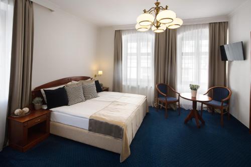 1 dormitorio con 1 cama grande, mesa y sillas en Fonte Hotel, en Győr