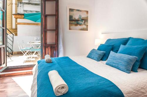 1 dormitorio con cama azul y almohadas azules en Abades Giralda Deluxe by Valcambre, en Sevilla