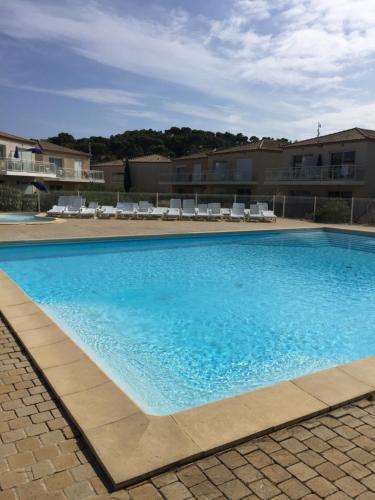 une grande piscine bleue avec des chaises longues blanches dans l'établissement Résidence les jardins du phoebus appartement, à Gruissan