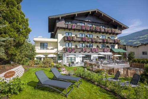 a large building with chairs in the grass at Hotel Landhaus Zillertal in Fügen