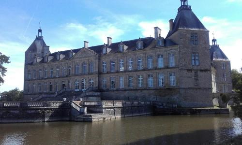 a large building in the middle of a body of water at Logis Saint Martin in Magny-lès-Villers