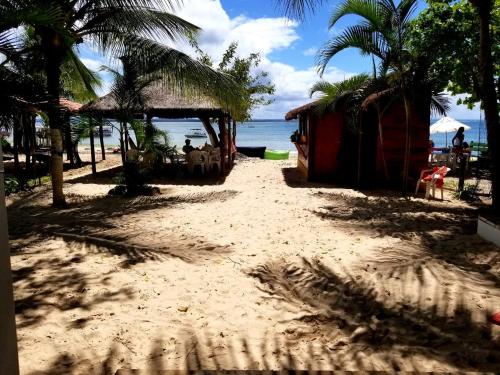 a beach with a hut and palm trees and the ocean at Pousada Boutique Recanto Do Encanto - GAMBOA - Morro de São Paulo in Morro de São Paulo