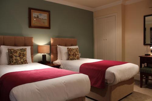 Habitación de hotel con 2 camas con sábanas rojas y blancas en The Dibbinsdale Inn, en Bromborough