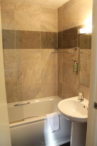 ein Badezimmer mit einem Waschbecken, einer Badewanne und einem WC in der Unterkunft The Dibbinsdale Inn in Bromborough