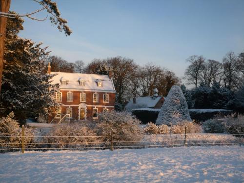 a house with a christmas tree in the snow at Brackenborough Hall Coach House - Stables in Louth