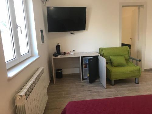 a room with a desk and a green chair and a television at vecchio frantoio in Spezzano Albanese