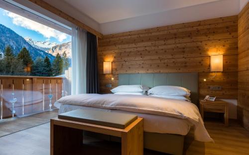 a bedroom with a bed and a large window at Hotel Europeo Alpine Charme & Wellness in Pinzolo