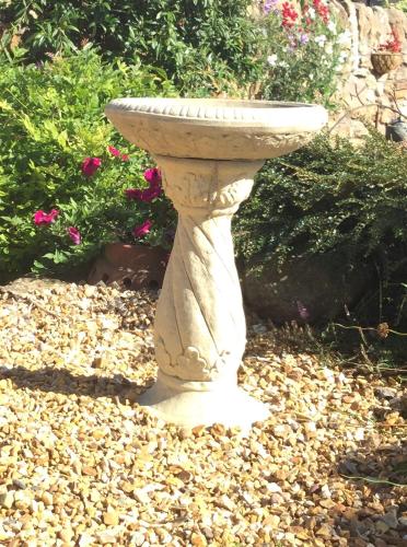 a stone bird bath sitting on a pile of rocks at Honeypot Guest House in Crail