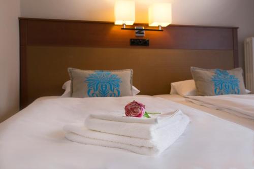 a pile of towels and a rose on a bed at Hotel Marttel in Karlovy Vary