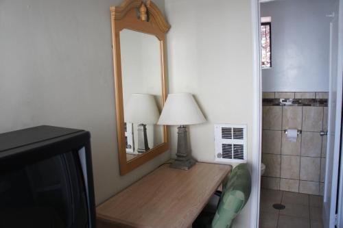 a room with a table with a lamp and a mirror at Budget Inn in El Cerrito