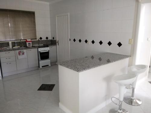 a white kitchen with a counter in the middle at CASA JE - Santa Cruz do Sul in Santa Cruz do Sul