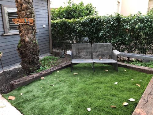 a chair sitting next to a tree in a yard at Hilltop Haven in Poriyya Illit
