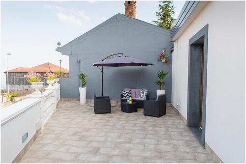 a patio with an umbrella and chairs and a table at Dolce Vita in Zafferana Etnea