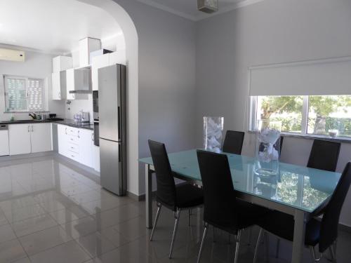 a kitchen with a glass table and black chairs at VILA FLAMINGO in Belmonte
