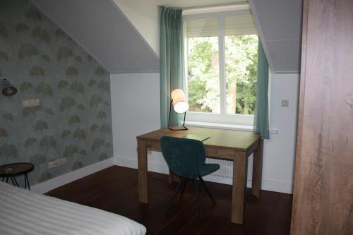 a bedroom with a desk and a window and a bed at Hotel De Hoefpoort in Gemert