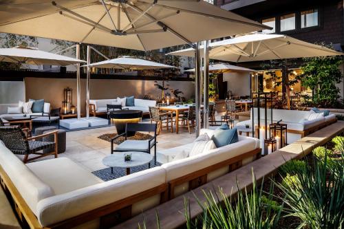 an outdoor patio with couches and tables and umbrellas at Ambrose Hotel in Los Angeles