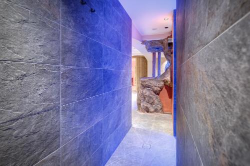 a blue tile hallway with a stone wall at Hotel Klostersepp in Chiusa
