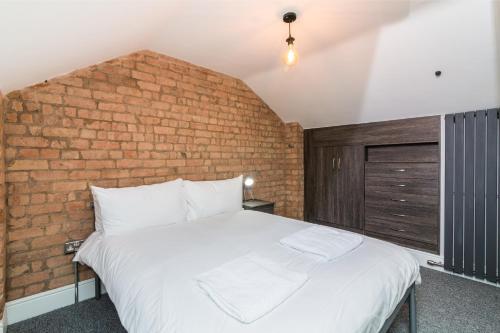 Cama en habitación con pared de ladrillo en Salisbury Street Guesthouse, en Long Eaton
