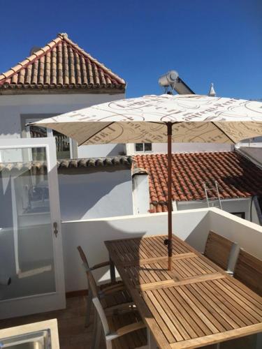 a wooden table with an umbrella on a balcony at Pessoa/Rico - Historical Tavira House in Tavira