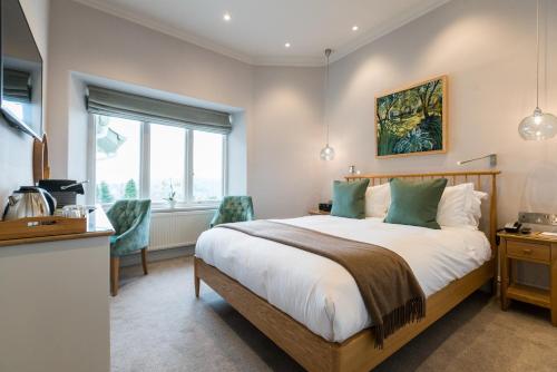 a bedroom with a bed and a desk and a window at Lindeth Fell Country House in Bowness-on-Windermere