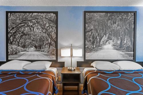 una habitación de hotel con 2 camas y una cruz en la pared en Super 8 by Wyndham Hardeeville, en Hardeeville