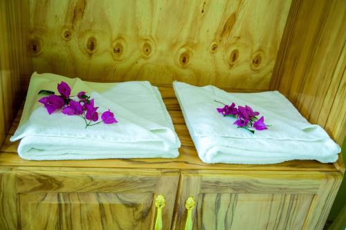 two white towels with purple flowers on them at Asmorein Hotel in Babati