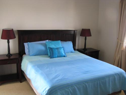um quarto com uma cama grande com lençóis azuis e 2 candeeiros em La Mer A em Margate