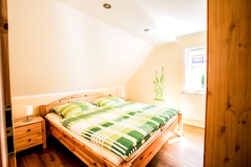 1 dormitorio con 1 cama con edredón verde y blanco en Ferienwohnung Im Schlossgarten Herbsleben, en Herbsleben