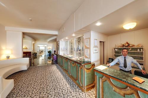 a man in a tie standing at a counter at Hotel Bahia in San Benedetto del Tronto