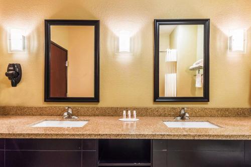 a bathroom with two sinks and two mirrors at Days Inn & Suites by Wyndham Mineral Wells in Mineral Wells