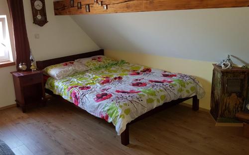 un dormitorio con una cama con un edredón floral en Apartma Lipek, en Pristava