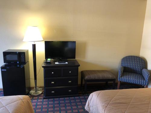a hotel room with a bed and a television and a chair at Americas Best Value Inn Maumee/Toledo in Maumee