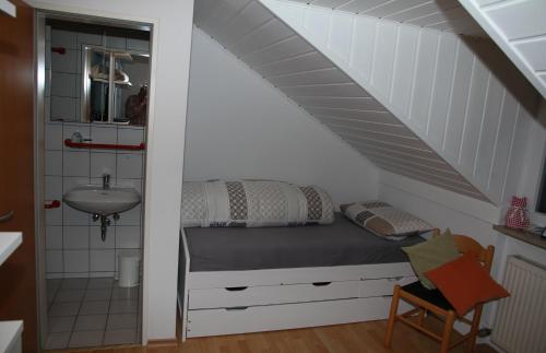 ein Schlafzimmer mit einem Bett und einem Waschbecken im Dachgeschoss in der Unterkunft Ferienhaus Adele in Zandt