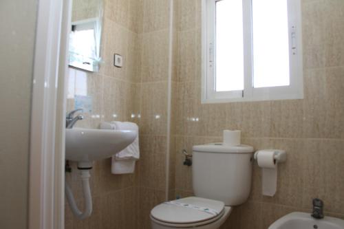 a bathroom with a toilet and a sink and a window at Hotel Trabuco in Santiago de la Ribera