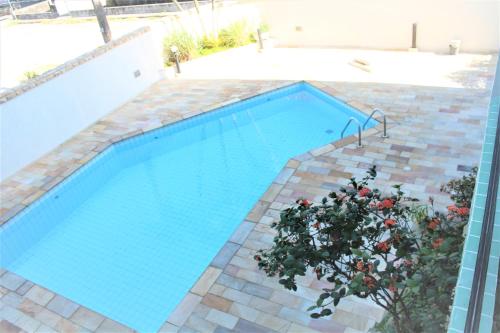 a swimming pool with a plant in front of it at Paraiso no Guarujá Enseada - Piscina - Ar Condicionado - WIFI - Garagem in Guarujá
