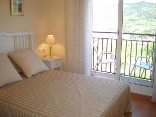 a bedroom with a bed and a balcony with a chair at CAL SOLÉ in Ulldemolins