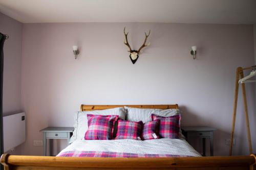 a bed with plaid pillows and a clock on the wall at Seal Cottage in Portree