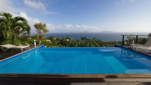 a swimming pool with a view of the ocean at Villa Cajou chambres d'hôtes chez l'habitant et Zanzibar cottage in Trois-Rivières