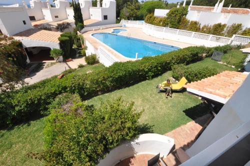 a person sitting on a lawn next to a swimming pool at Rustic Beach House at the Cliff T3 | C218 in Porches