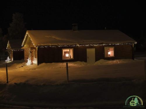 a house covered in lights in the snow at night at Lapland Stuga & Tours in Rentjärn