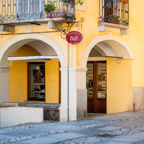 a yellow building with two arches and a store at B&B Al Vicolo del Gallo in Varallo