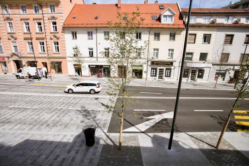 een witte auto die door een stadsstraat met gebouwen rijdt bij Apartment Optim in Ljubljana
