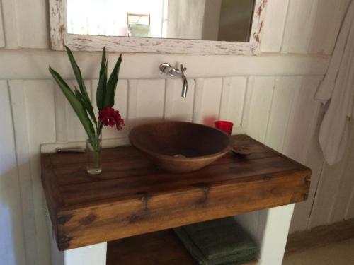 a wooden sink on a wooden table with a vase of flowers at Trancoso Jungle Lodge in Trancoso