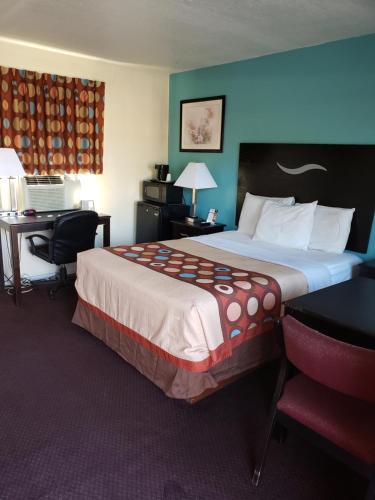 ein Hotelzimmer mit einem großen Bett und einem Schreibtisch in der Unterkunft American Inn in Sedalia