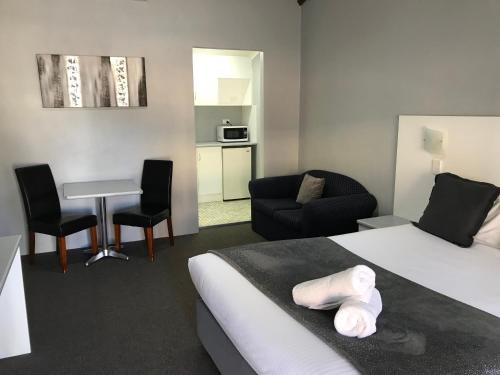a hotel room with a bed and a table and chairs at Hideaway Motor Inn in Armidale