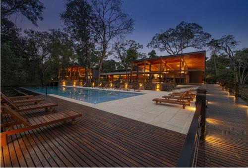 a house with a swimming pool and wooden benches at Selvaje Lodge Iguazu in Puerto Iguazú